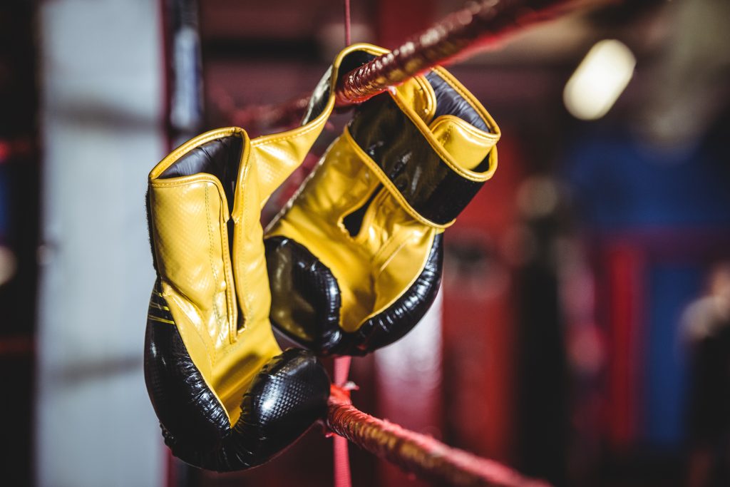 Pair of yellow boxing gloves hanging off the boxing ring